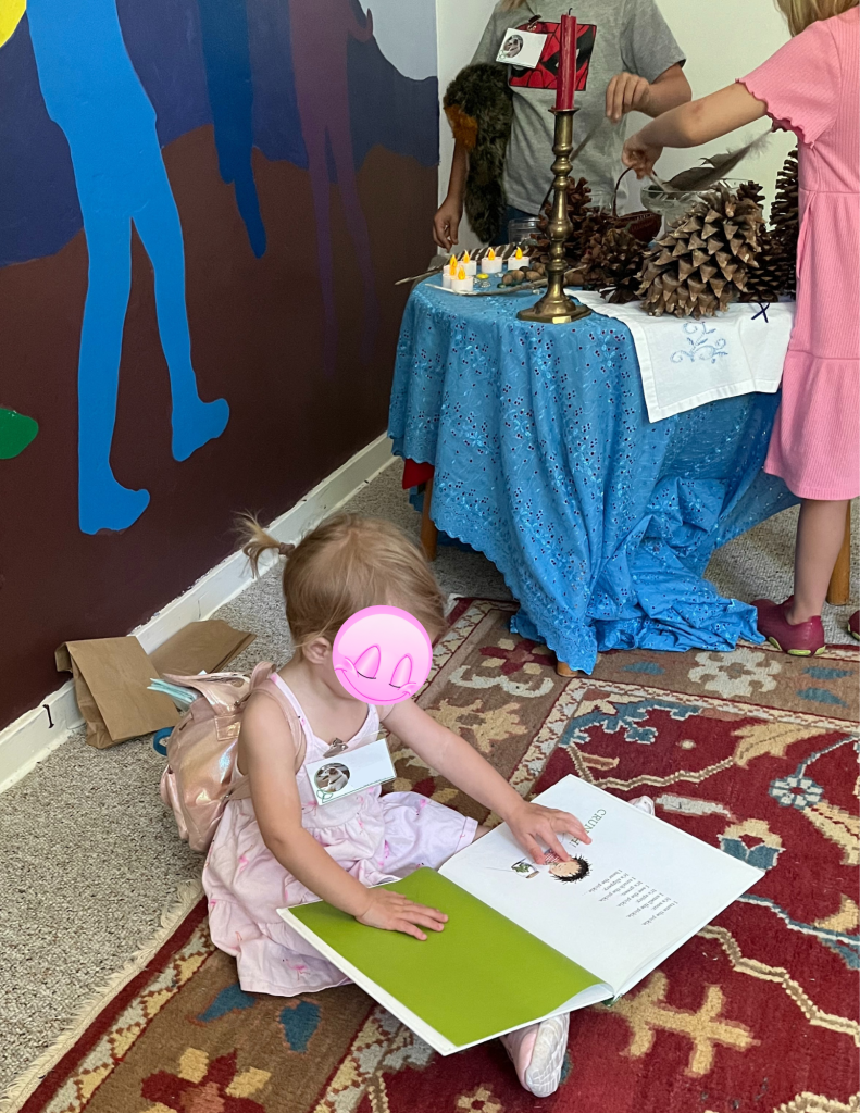small child looking at book while older children build altar behind
