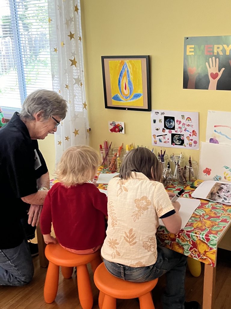 Jenny Dewey with two young people in their "studio" making drawings in Kids' Connection