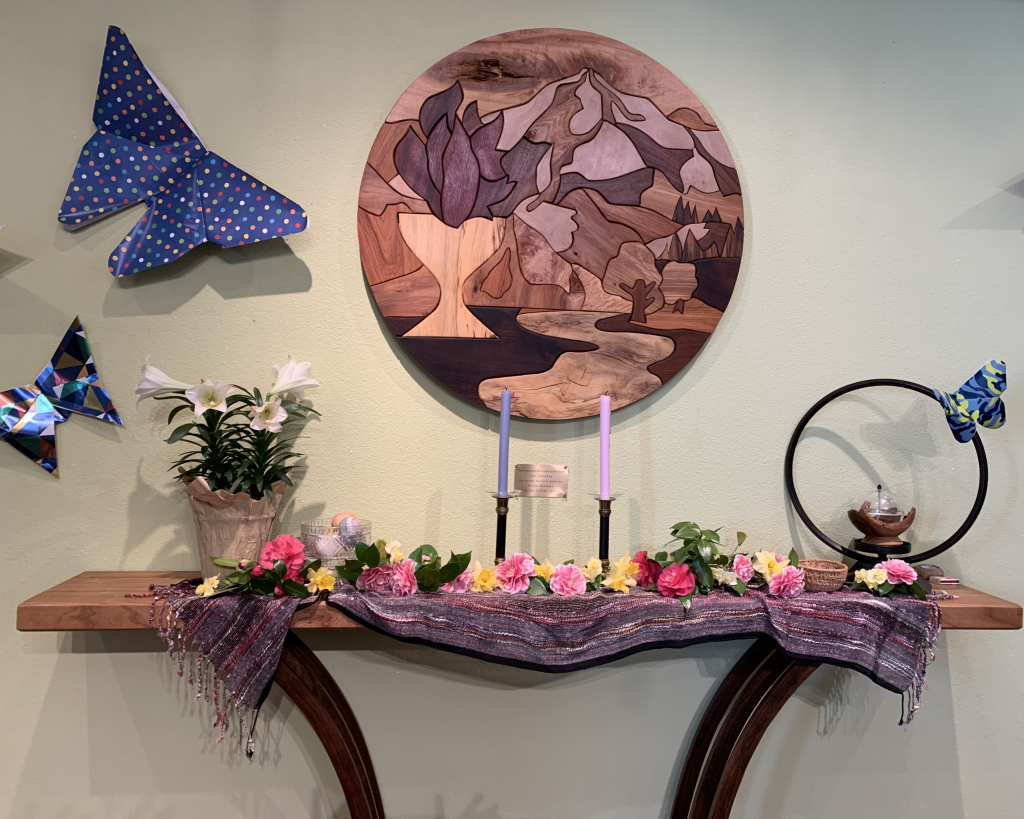 altar with wooden logo chancel piece, giant origami butterflies, and flowers
